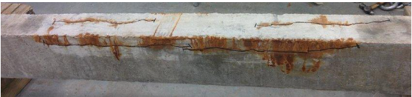 Cracks in a concrete beam with visible corrosive elements